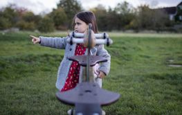 Concerned little girl pointing behind a seesaw on the...