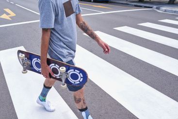 Man, hands and walking with skateboard in city on...