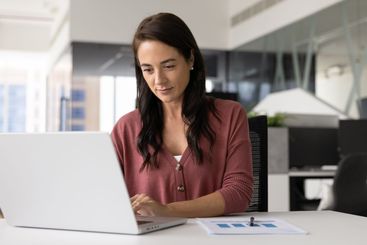 Focused positive business professional woman working on...