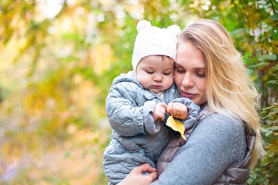 Mother and her little daughter play cuddling on autumn...