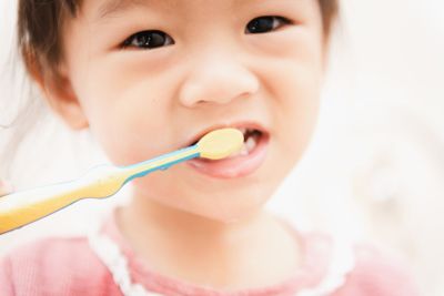 Sweet Asian child little girl brushing her teeth in...