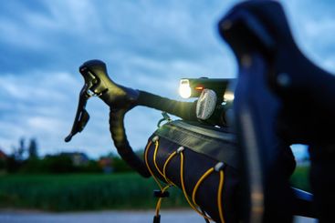 Bicycle handlebar with bike light on country road at dusk