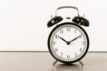 Black vintage alarm clock on wooden table