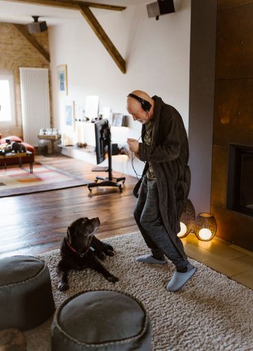 Senior man dancing while standing near dog on carpet at...