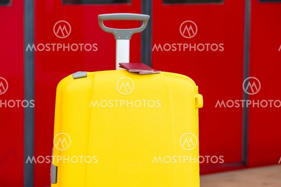 Closeup red passports on yellow luggage at train station