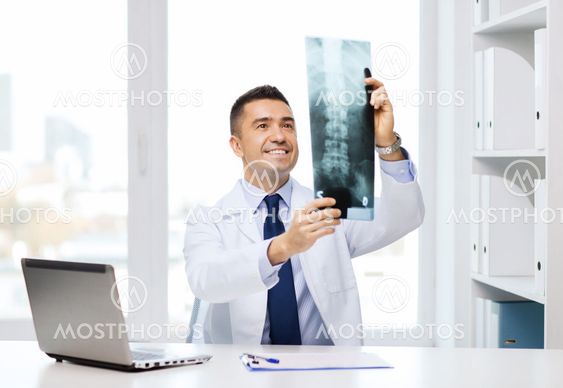 smiling male doctor in white coat looking at x-ray