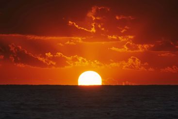 Sunset over ocean with dramatic clouds at dusk