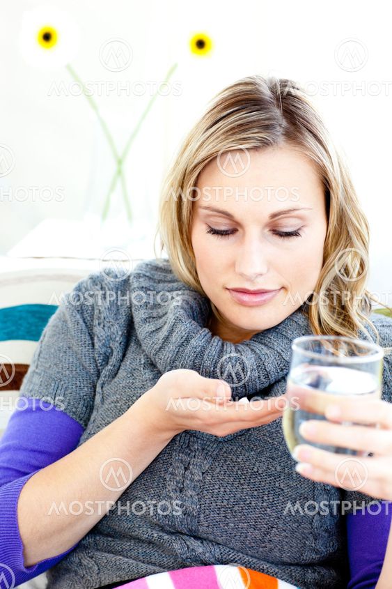 Sick woman taking pills holding a glass of water