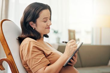 Home, pregnancy and woman on chair, notebook and writing...