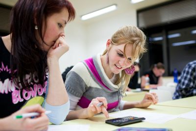 pretty female college student sitting in a classroom full...