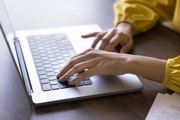 Woman working remotely using laptop, close up shot