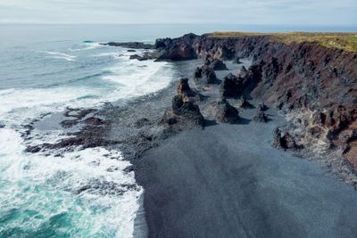 aerial view of rocky seashore and waves with foam,...