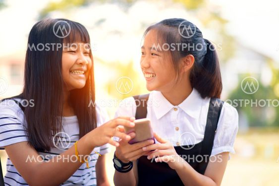 two asian teenager laughing with happiness face reading...