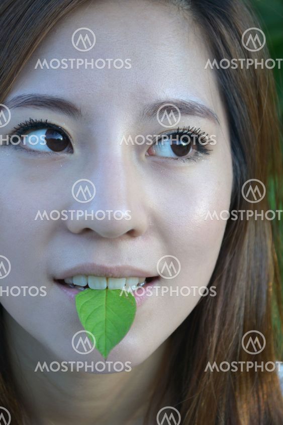 Beautiful young asian women with a leaf in mouth