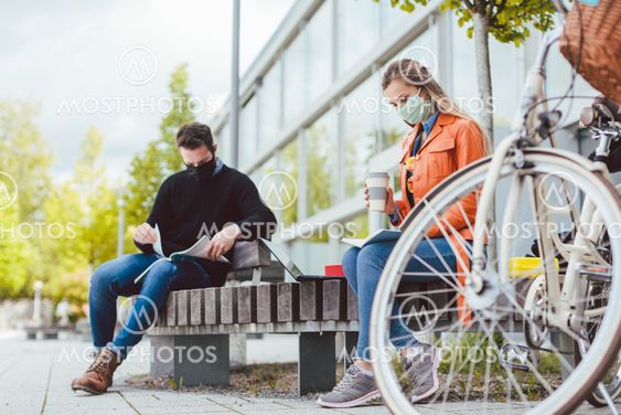 Two college students learning while keeping social distance