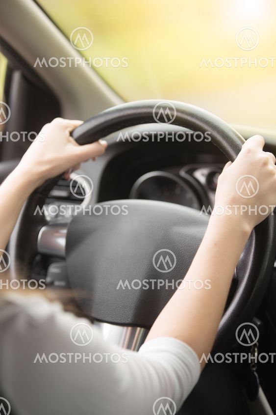 Close-up of female hands hold on the steering wheel