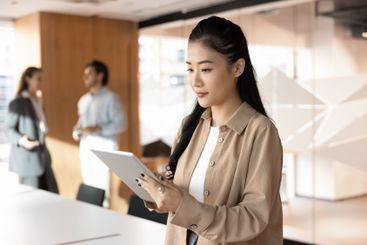 Focused young Asian manager girl using web technology on...