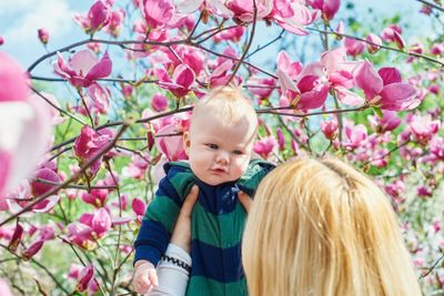 mother walking with her baby son in garden of blooming...
