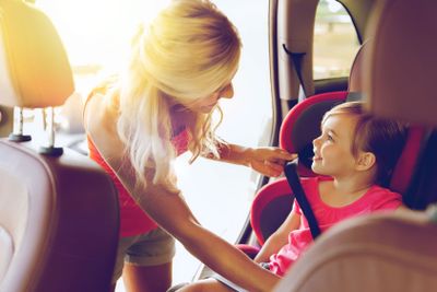 happy mother fastening child with car seat belt