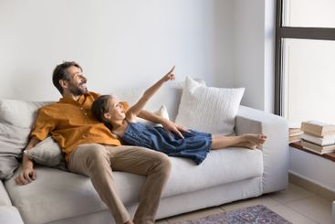 Joyful man and little daughter relaxing on white,...