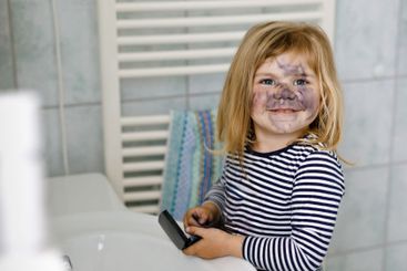 Funny little toddler girl using mother's make up and...