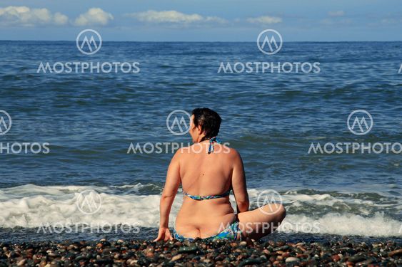 Woman sitting on shore of the sea on the beach