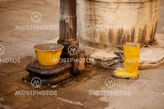 Yellow bucket and work boots near water
