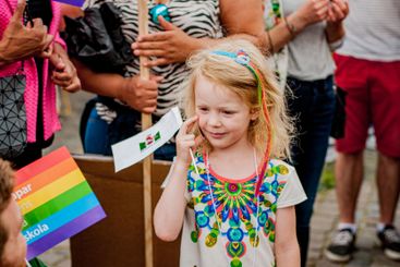 Flicka i prideparad med Malmö stad-flagga i handen