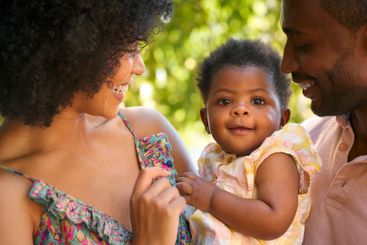 Close Up Of Loving Parents Cuddling Baby Daughter...