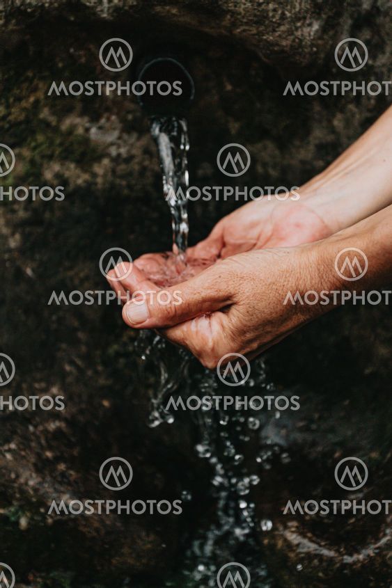 Close up of two old hands taking water to drink from a...
