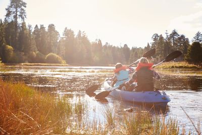 Mother and daughter kayaking on lake, back view