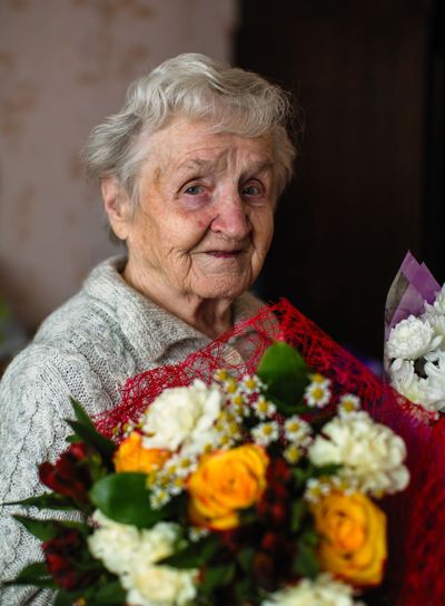An old woman with a bouquet of flowers.