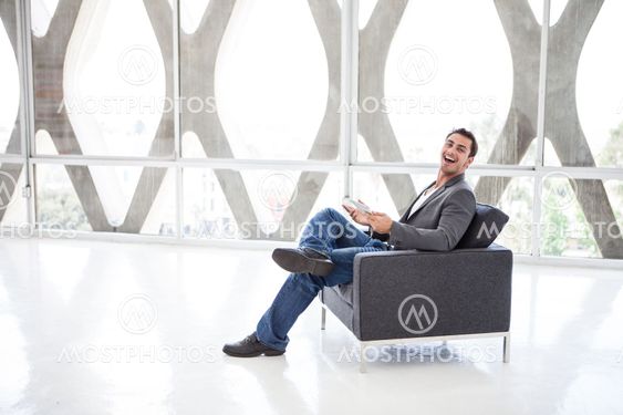 Good looking man laughing working on a mini think pad
