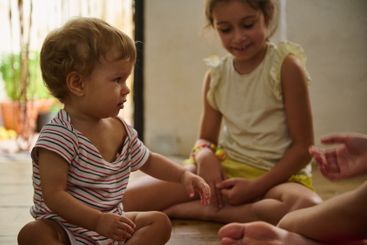 Two children playing indoors on a sunny day with wooden...