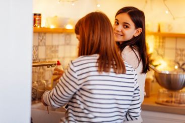 Two cute teenage girls are washing dishes after cooking...