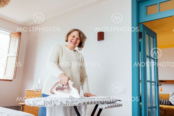 Close-up of an elderly woman ironing clothes on an...