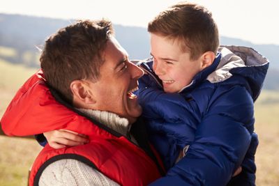 Father carrying son outdoors in countryside, close up