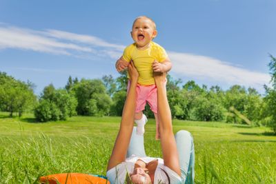 Happy mother lifting baby up with straight arms