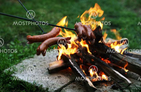 Roasting sausages on campfire in the garden