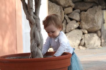 Funny baby girl 1 year old playing in the yard outdoors