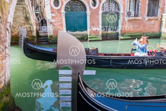Gondola parked in Venice canal with tourists enjoying city visit