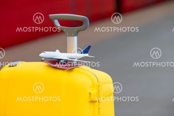 Red passports and airplane small model on yellow luggage...