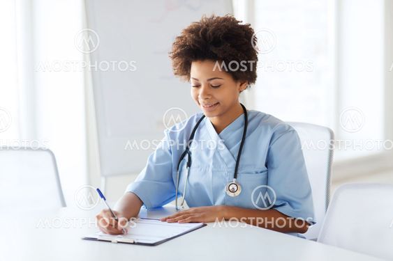 happy female doctor or nurse writing to clipboard