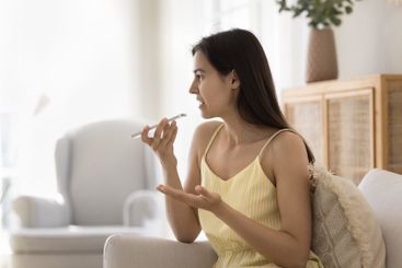 Pretty young girl sit on sofa dictate voicemail on...