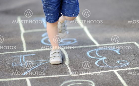 Closeup of little boy's legs and hopscotch drawn on asphalt