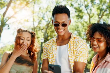 Smartphone, holiday and friends laughing in park for...
