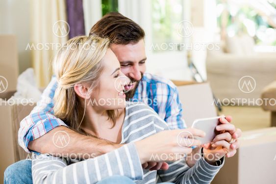 Couple using mobile phone in living room