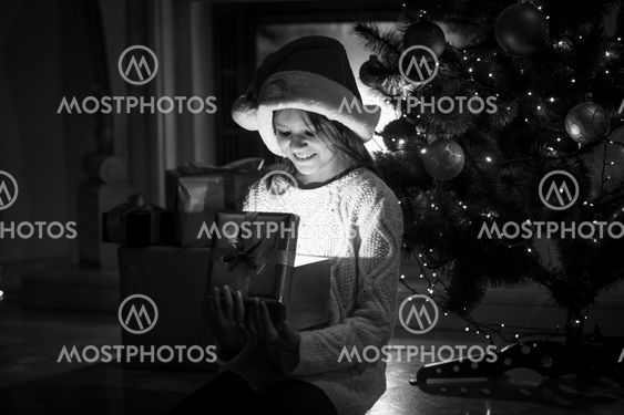 smiling girl looking inside of glowing gift box at...