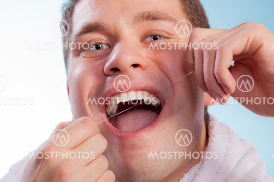 Young man cleaning her white teeth with dental floss