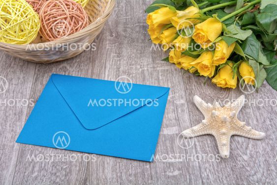 Envelope, starfish and roses on a wooden background